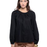 Model is wearing a black ALEKSA blouse paired with camel pants on a white background.