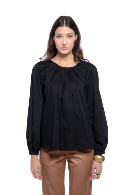 Model nosi crnu ALEKSA bluzu uparenu sa kamel pantalonama na beloj pozadini.