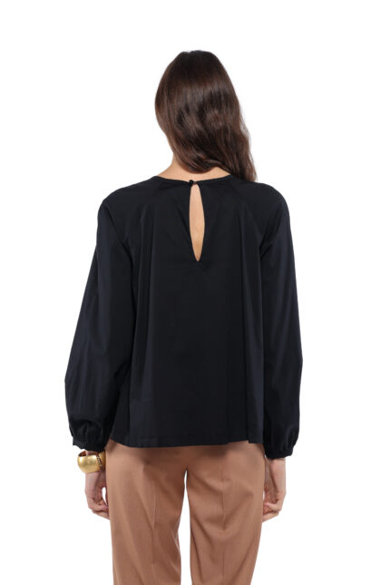 Model nosi crnu ALEKSA bluzu uparenu sa kamel pantalonama na beloj pozadini.