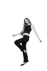 The model is wearing a black halter top paired with black pants.