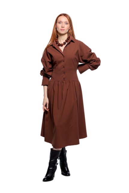 Devojka nosi midi braon haljinu sa dugim rukavima.