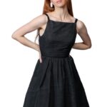 Devojka nosi crnu midi haljinu na bretele.