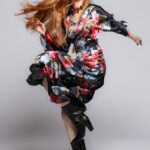 The girl is wearing a black midi dress with a floral pattern and kimono sleeves.