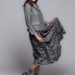 The model is wearing a floral-patterned midi skirt paired with a gray blazer.