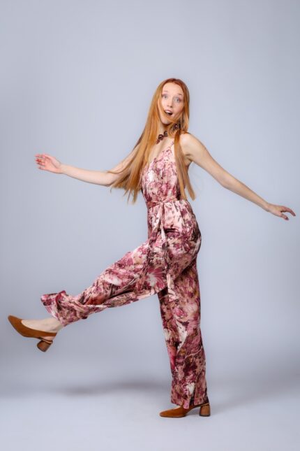 Devojka nosi dugi dezenirani prljavo roze kombinezon