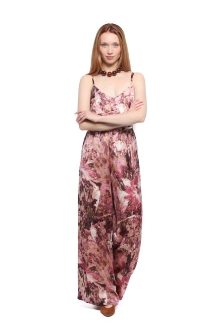 The model is wearing a long patterned dusty pink jumpsuit.