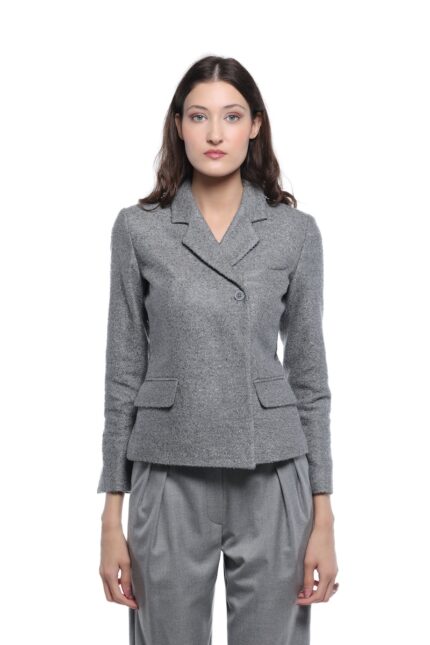 Model nosi sivi GIGI blejzer sa klasičnim reverima, jednim dugmetom i džepovima sa patnama. Blejzer je uparen sa sivim širokim pantalonama na beloj pozadini.
