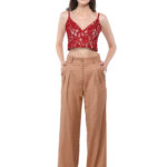 The model is wearing camel trousers paired with a red lace top.