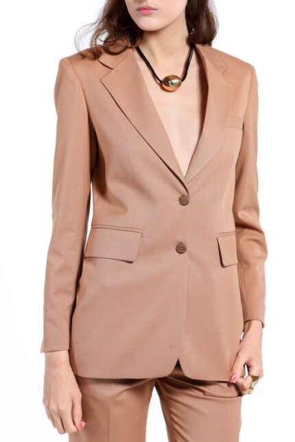 Model nosi LETITIA strukirani sako u toploj kamel boji sa širokim klasičnim reverima i dvorednim kopčanjem sa dva dugmeta. Sako ima prednje džepove sa patnama i blago oblikovanu siluetu. Uparen je sa pantalonama u istoj nijansi na beloj pozadini.