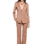 Model nosi LETITIA strukirani sako u toploj kamel boji sa širokim klasičnim reverima i dvorednim kopčanjem sa dva dugmeta. Sako ima prednje džepove sa patnama i blago oblikovanu siluetu. Uparen je sa pantalonama u istoj nijansi na beloj pozadini.