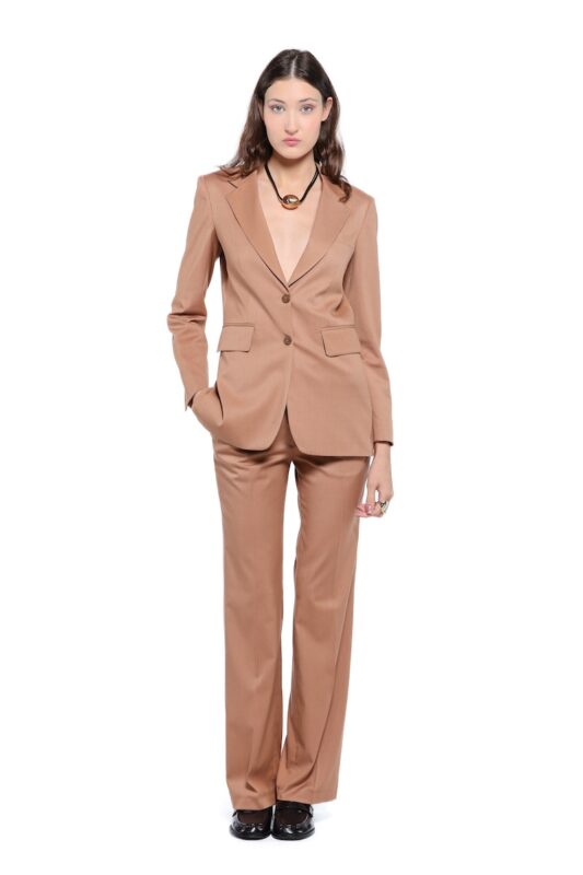 Model nosi LETITIA strukirani sako u toploj kamel boji sa širokim klasičnim reverima i dvorednim kopčanjem sa dva dugmeta. Sako ima prednje džepove sa patnama i blago oblikovanu siluetu. Uparen je sa pantalonama u istoj nijansi na beloj pozadini.