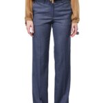 Devojka nosi pantalone od plavog štofa u kombinaciji sa bež bluzom.