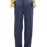 Devojka nosi plave pantalone sa faltama i širokim nogavicama i zelenu bluzu.