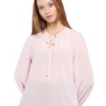 Devojka nosi puder roze svilenu košulju sa dugim rukavima.