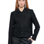 Devojka nosi crni blejzer sa kragnom i prednjim džepovima u kombinaciji sa crnim pantalonama.