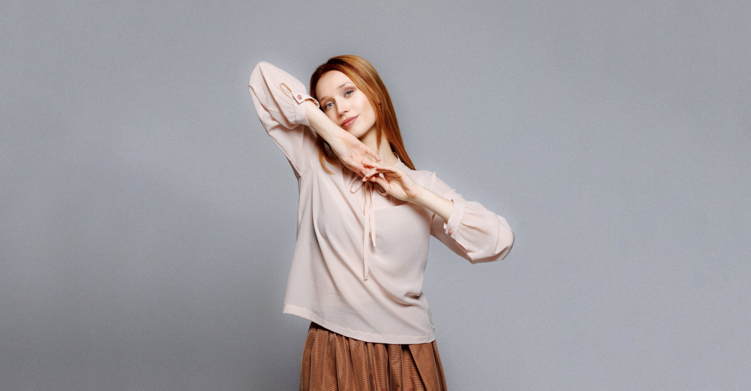 Devojka nosi puder roze svilenu košulju sa dugim rukavima.