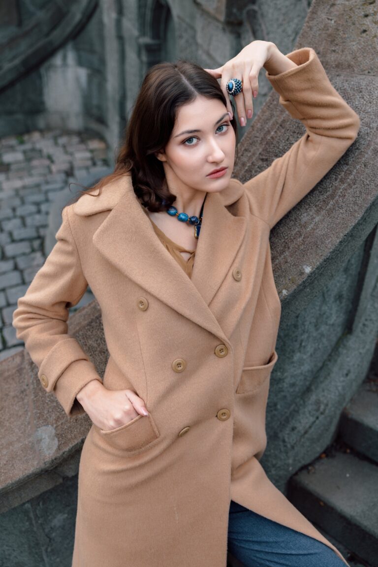 Devojka nosi bež kaput sa dvorednim kopčanjem.
